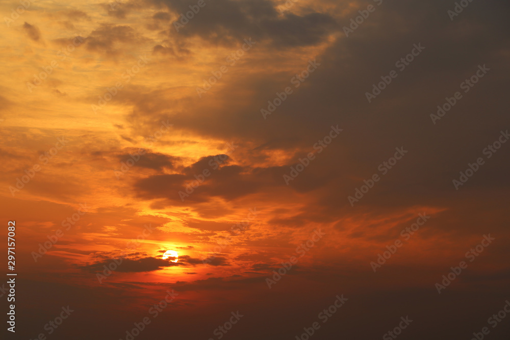 Sunset on colorful dramatic sky, sun shining through the dark clouds. Picturesque landscape for background