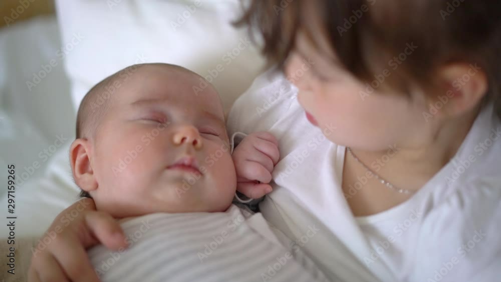 Big sister holding her newborn sister in her arms, taking care of little sister. Concept of love and child care. Big sister holding her newborn sister in her arms, taking care of little sister. Concept of love and child care.