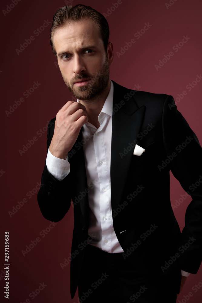 Fototapeta premium Concerned groom arranging his collar and looking forward