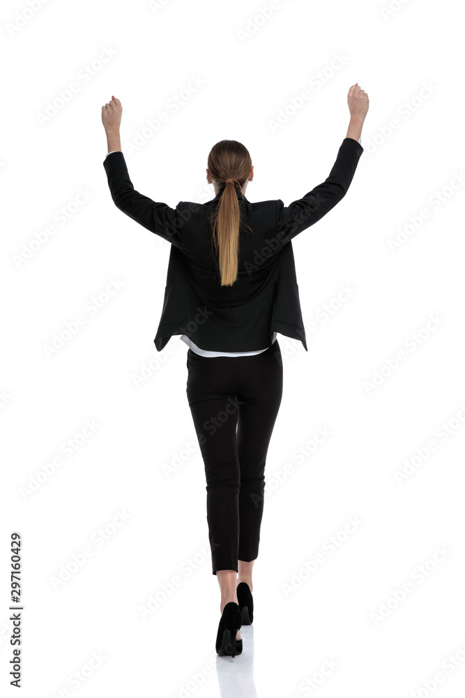 businesswoman walking with hands up in the air victorious