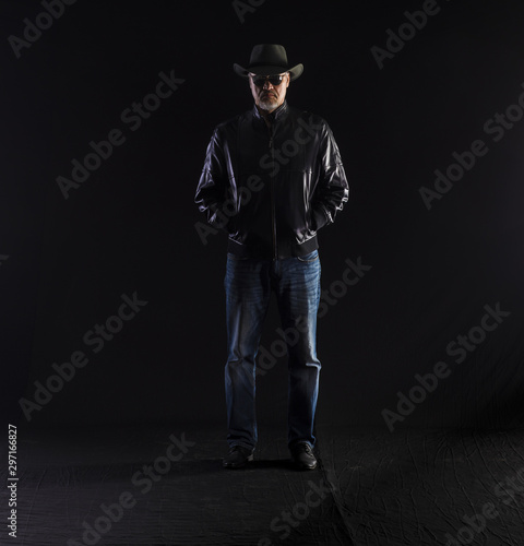 man in hat and black leather jacket on a black background