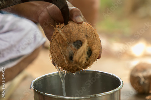 Man using knife to chopped fresh coconut for drink and green coconuts background,