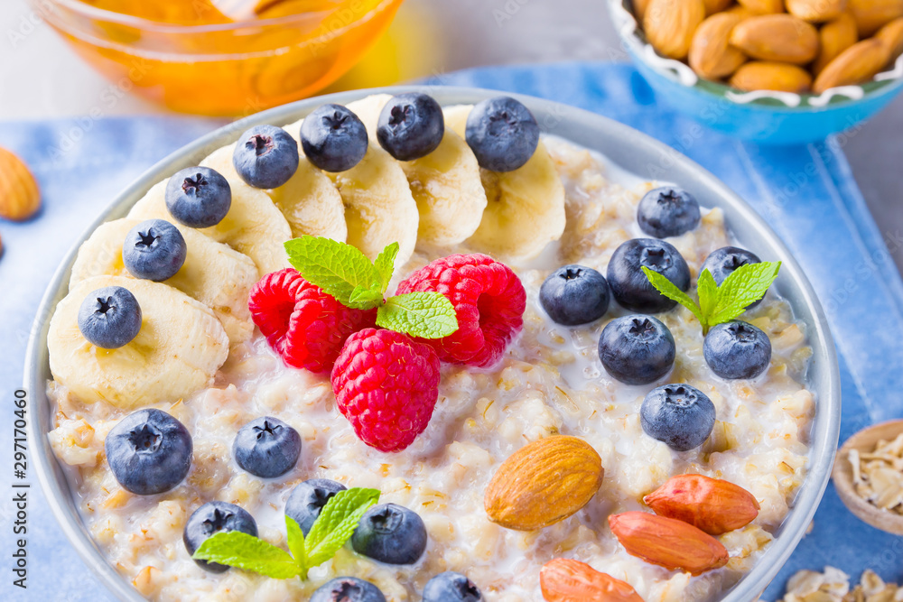 Healthy homemade oatmeal with berries and nuts for breakfast. Oatmeal with fruits, nuts and honey. Oatmeal with blueberries, banana and raspberries Healthy homemade oatmeal with berries and nuts for breakfast. Oatmeal with fruits, nuts and honey. Oatmeal with blueberries, banana and raspberries