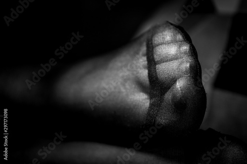 A close up black and white potrait of a girls pantyhose feet and the reinforced toe on a couch indoor.