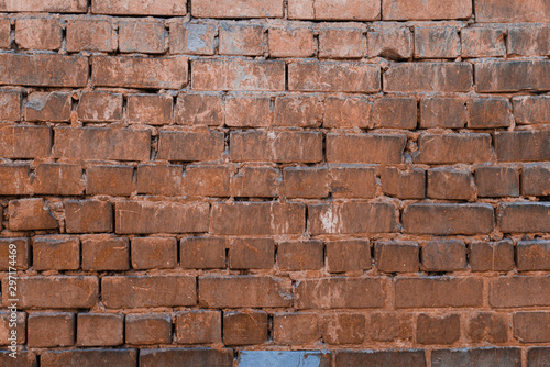 Texture of brick wall with peeling orange-and-gray paint