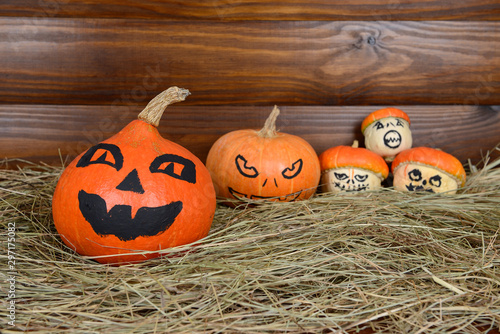 The orange pumpkins painted for Halloween on hay and wooden background photo