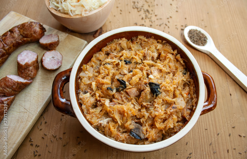 Bigos w naczuniu z kamionki, obok składniki bigosu: kiełbasa, kiszona kapusta i kminek Bigos w naczuniu z kamionki, obok składniki bigosu: kiełbasa, kiszona kapusta i kminek