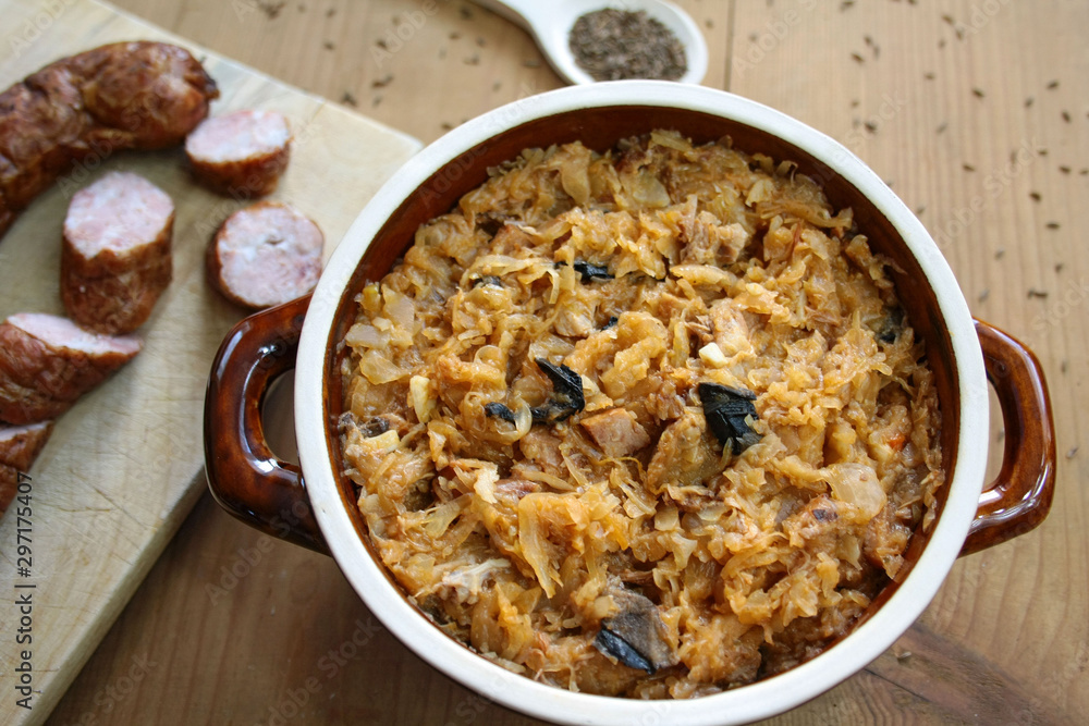 Bigos in stoneware dish and bigos ingredients: sausage, sauerkraut and cumin Bigos in stoneware dish and bigos ingredients: sausage, sauerkraut and cumin