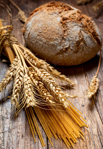 Pasta and wholemeal bread with ears of wheat on the rustic wooden table