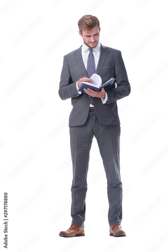 in full growth. young businessman making notes in a notebook. in full growth. young businessman making notes in a notebook.
