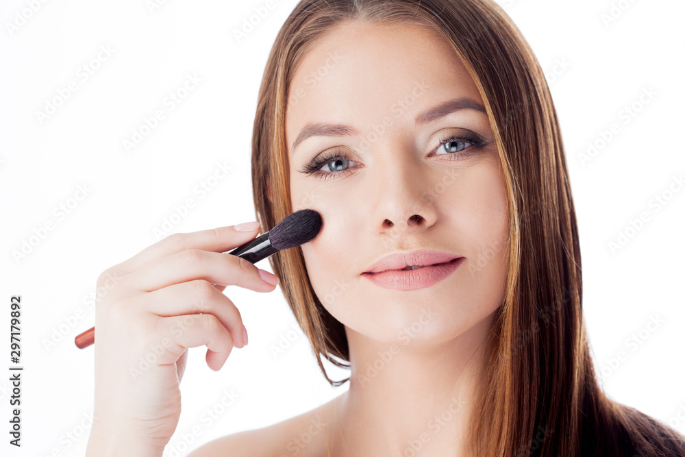 Use the powder. Attractive girl doing makeup. Portrait of a beautiful young woman using a brush for Foundation