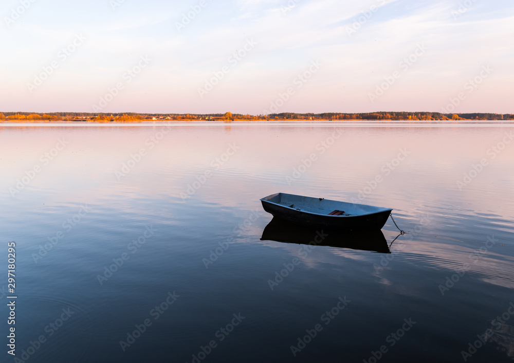Small boat in the lake at evening sky Small boat in the lake at evening sky