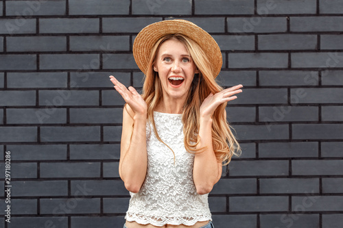 Freestyle. Young woman in hat standing isolated on wall hands aside shouting excited