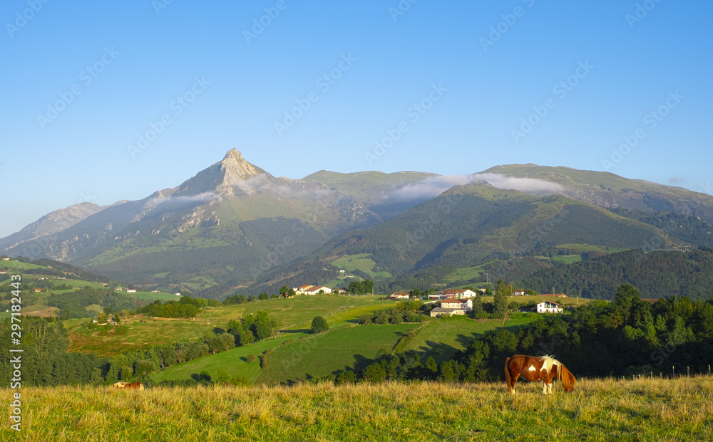 Horse grazing in meadows of Lazkaomendi with the Sierra de Aralar and Mount Txindoki in the background.