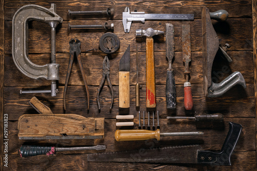 Old carpentry work tools on a brown wooden table background.