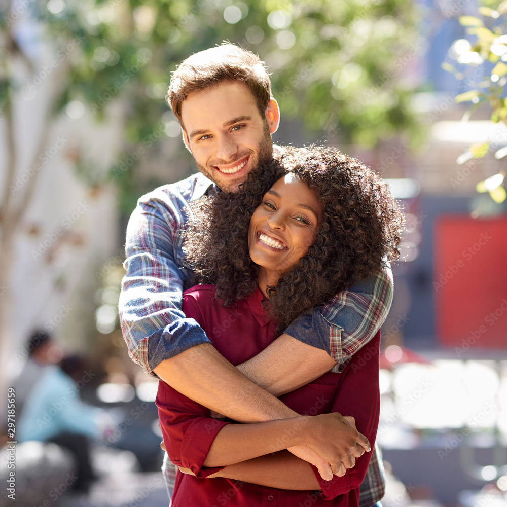 Diverse young couple affectionately standing together in the city Diverse young couple affectionately standing together in the city