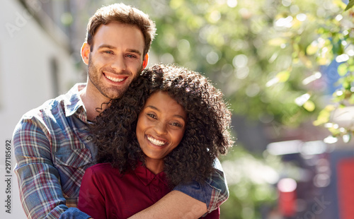 Diverse couple affectionately standing together ouside on a sunny day