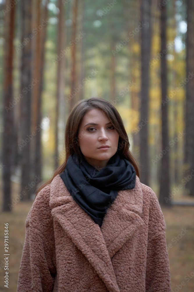 Beautiful girl in a coat and with a scarf posing in the autumn forest. Beautiful girl in a coat and with a scarf posing in the autumn forest.
