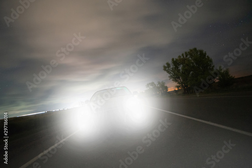 Photography the car rushing along the night highway dazzles with the high beam its headlight