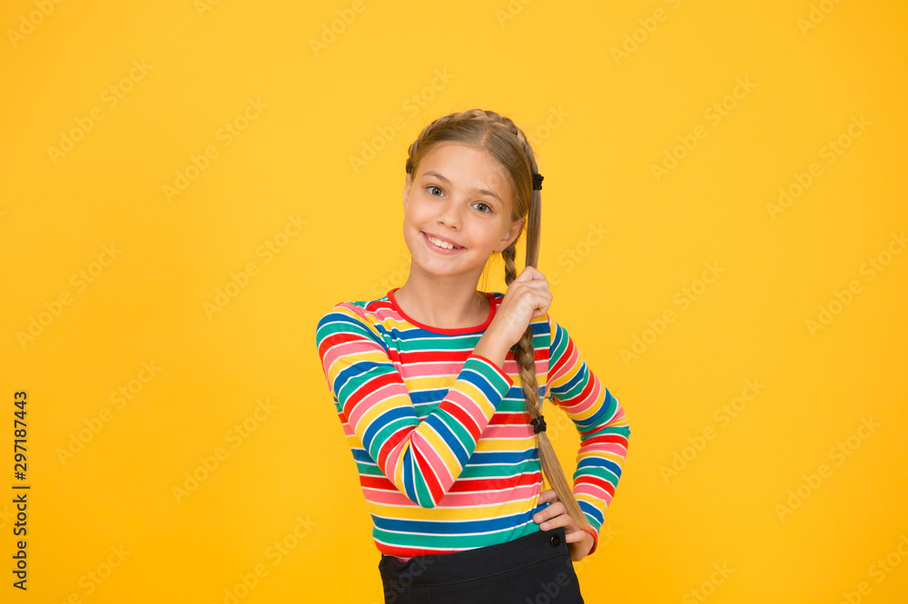 Braiding hair. Adorable little girl with plaited hair yellow background. Cute small child hold long hair braid. Luxurious hair extensions. Beauty salon. Haircare and hairstyling Braiding hair. Adorable little girl with plaited hair yellow background. Cute small child hold long hair braid. Luxurious hair extensions. Beauty salon. Haircare and hairstyling