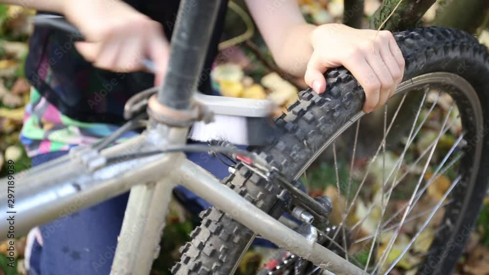 Young girl cleaning her bicycle with brush. Young girl cleaning her bicycle with brush.