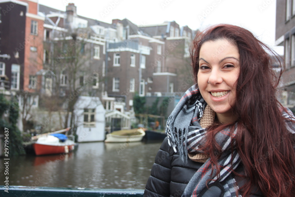 red-haired Caucasian girl in autumn or winter season dressed in warm clothes for the cold between the streets of Amsterdam