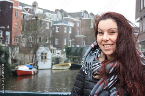 red-haired Caucasian girl in autumn or winter season dressed in warm clothes for the cold between the streets of Amsterdam