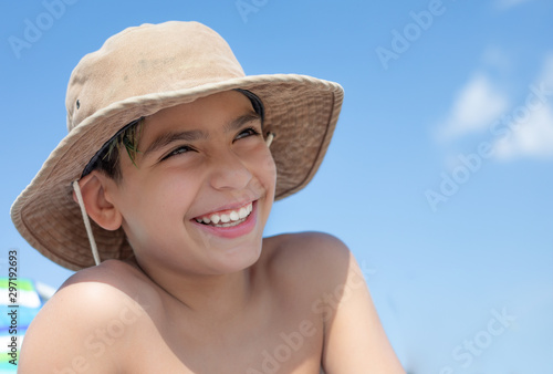 Boy smiling looking upward and wearing a hat