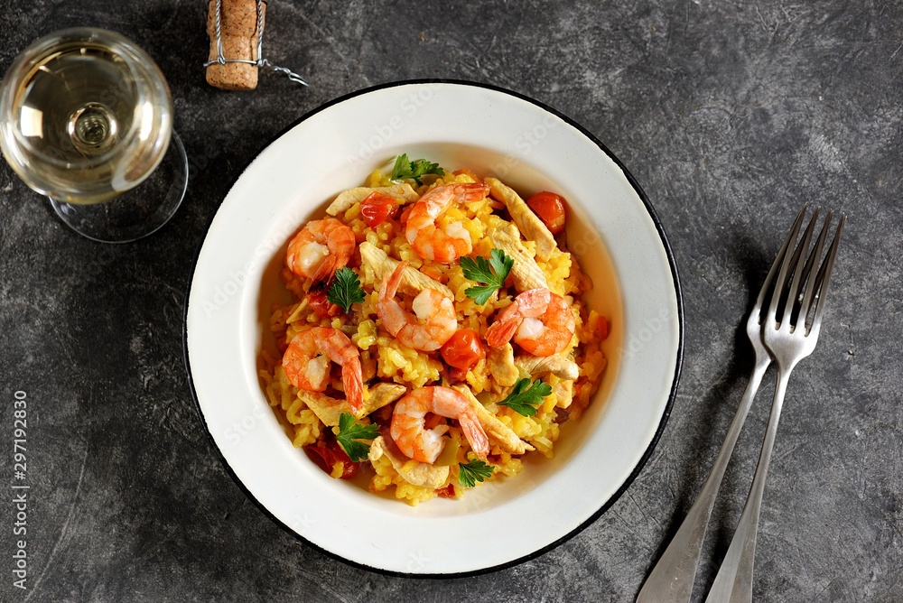 Paella or risotto with chicken breast, shrimp tails, carrots, onions, cherry tomatoes, white wine and chicken stock. Top view. 