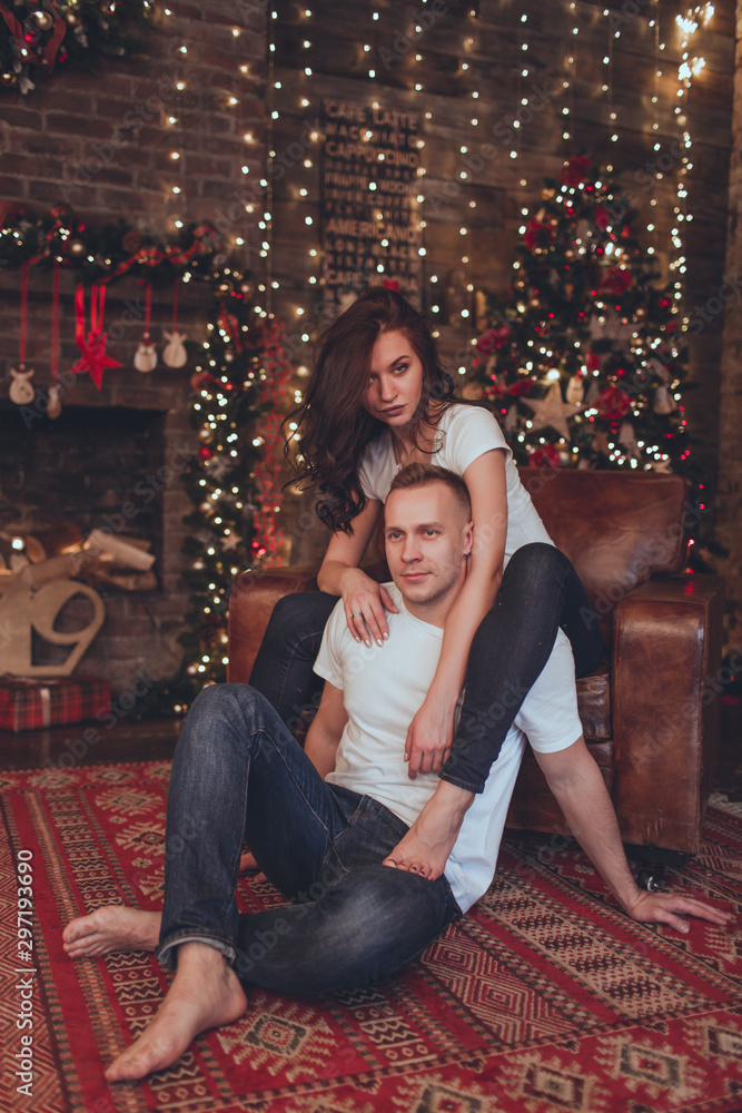 Lovely beautiful couple woman and man are sitting at home near fireplace. Christmas time.