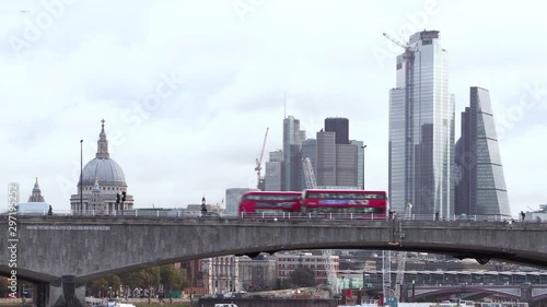 Two red buses pass on bridge by St. Paul's Cathedral photo