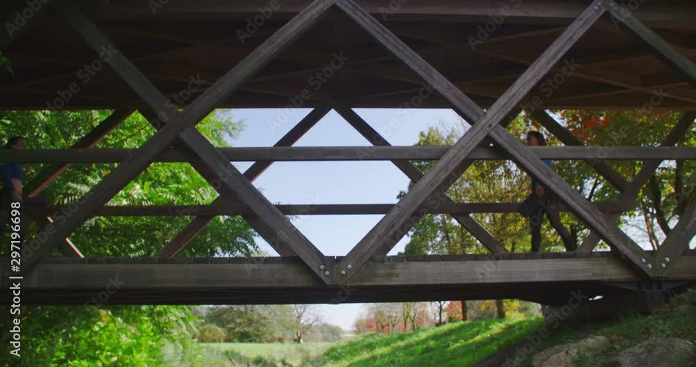 Two women meet and greet on the bridge in slow motion, park and forrest in background. 4K. Two women meet and greet on the bridge in slow motion, park and forrest in background. 4K.