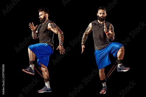 Young athlete squatting exercise with resistance band around legs. Full body length over black studio background. Isolate