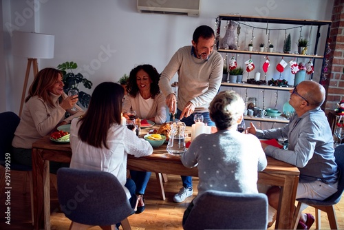 Family and friends dining at home celebrating christmas eve with traditional food and decoration, preparing turkey for dinner