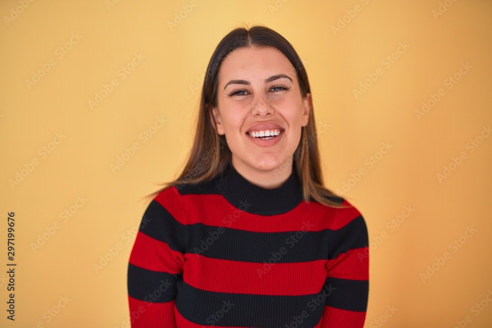 Young beautiful woman smiling happy wearing a sweater over isolated yellow background Young beautiful woman smiling happy wearing a sweater over isolated yellow background
