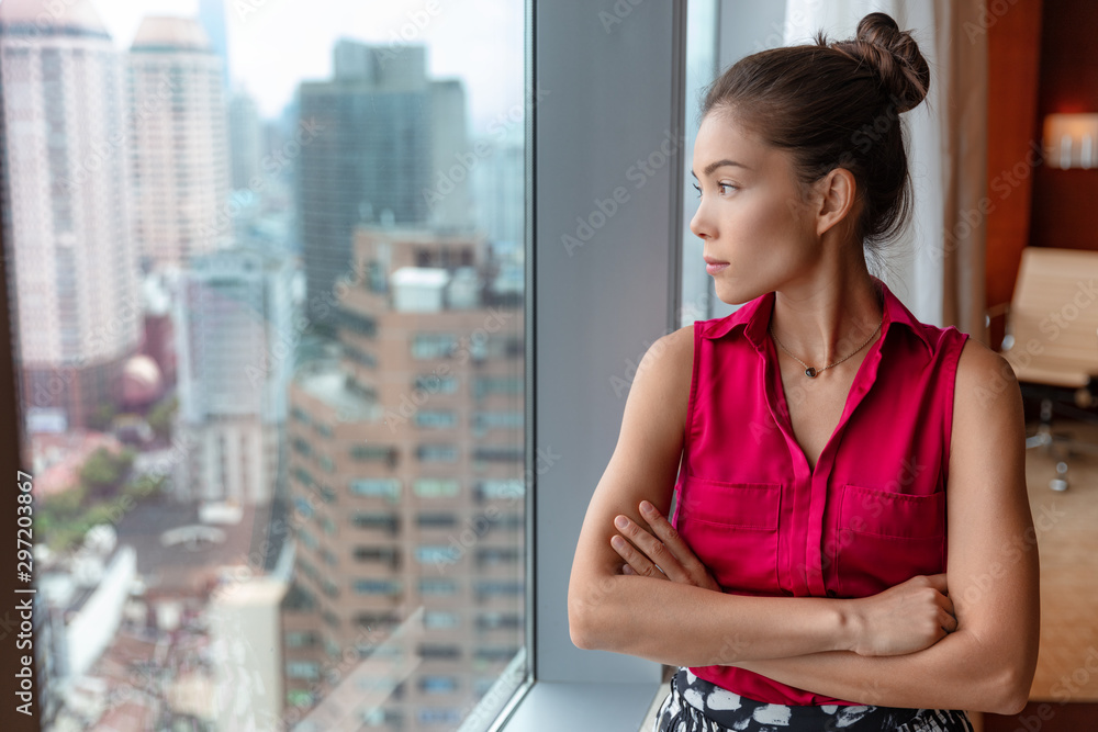 Office business woman worker taking a break pensive looking out the window thinking of future ideas. Asian businesswoman confident looking at skyline in city center in China, Asia. Office business woman worker taking a break pensive looking out the window thinking of future ideas. Asian businesswoman confident looking at skyline in city center in China, Asia.