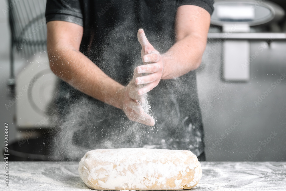 Fototapeta premium Baker claping hands with flour in restaurant kitchen .