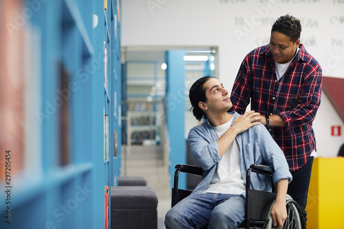 Fotografi Portrait of two college students, one of them in wheelchair, looking at each oth