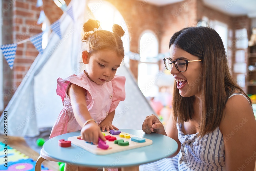 Young beautiful teacher and toddler learning maths playing with numbers puzzle at kindergarten Young beautiful teacher and toddler learning maths playing with numbers puzzle at kindergarten