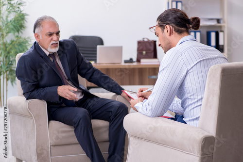 Fototapeta Naklejka Na Ścianę i Meble -  Old man visiting young male doctor psychologist