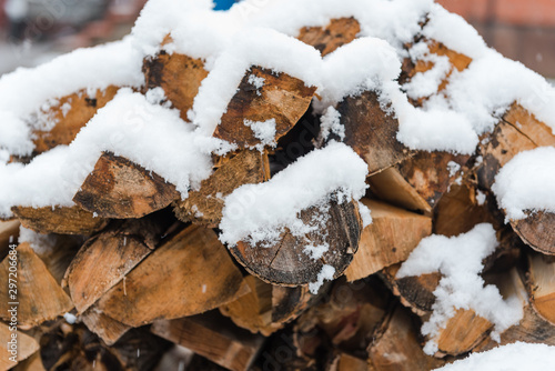 Firewood under the snow. Dry firewood. Firewood on the street. Snow. Use the stove. Firewood in the village.