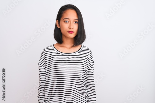 Young chinese woman wearing striped t-shirt standing over isolated white background Relaxed with serious expression on face. Simple and natural looking at the camera. © Krakenimages.com