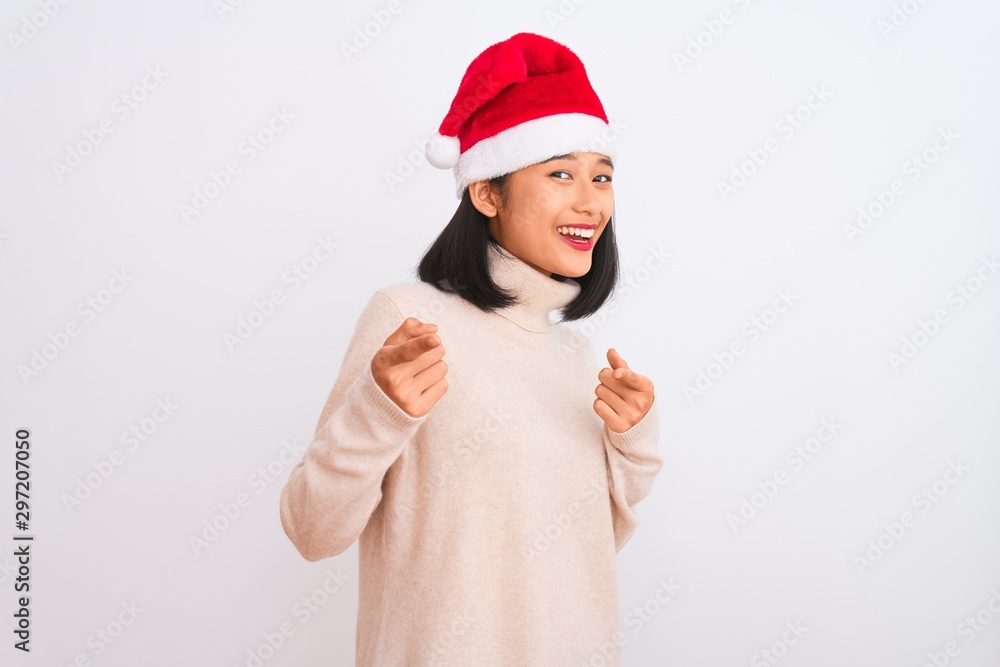 Young beautiful chinese woman wearing Christmas Santa hat over isolated white background pointing fingers to camera with happy and funny face. Good energy and vibes.