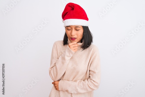 Young beautiful chinese woman wearing Christmas Santa hat over isolated white background feeling unwell and coughing as symptom for cold or bronchitis. Healthcare concept.