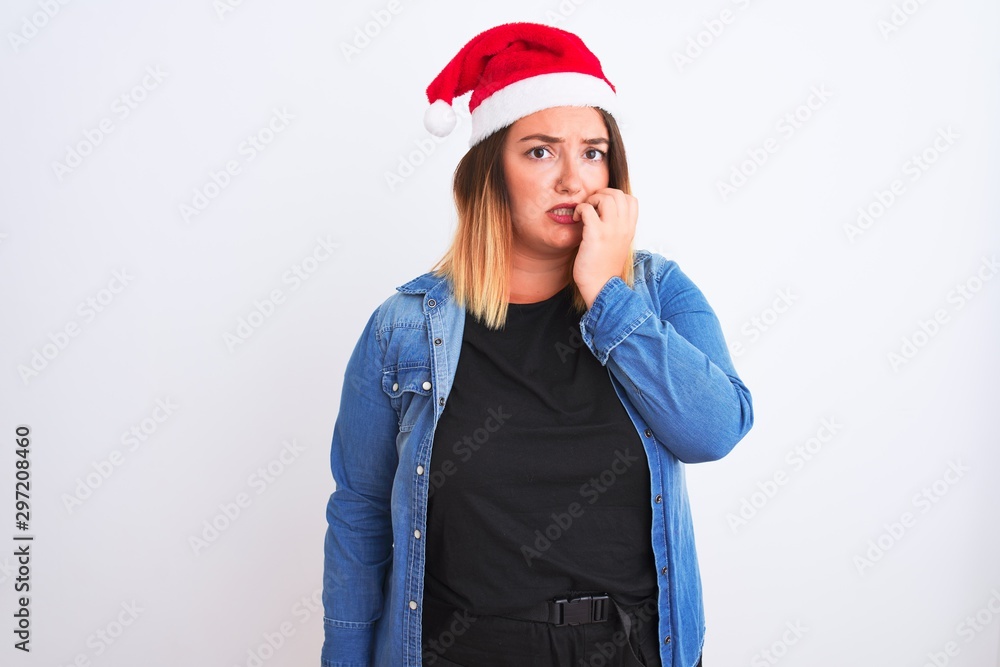 Young beautiful woman wearing Christmas Santa hat standing over isolated white background looking stressed and nervous with hands on mouth biting nails. Anxiety problem. Young beautiful woman wearing Christmas Santa hat standing over isolated white background looking stressed and nervous with hands on mouth biting nails. Anxiety problem.