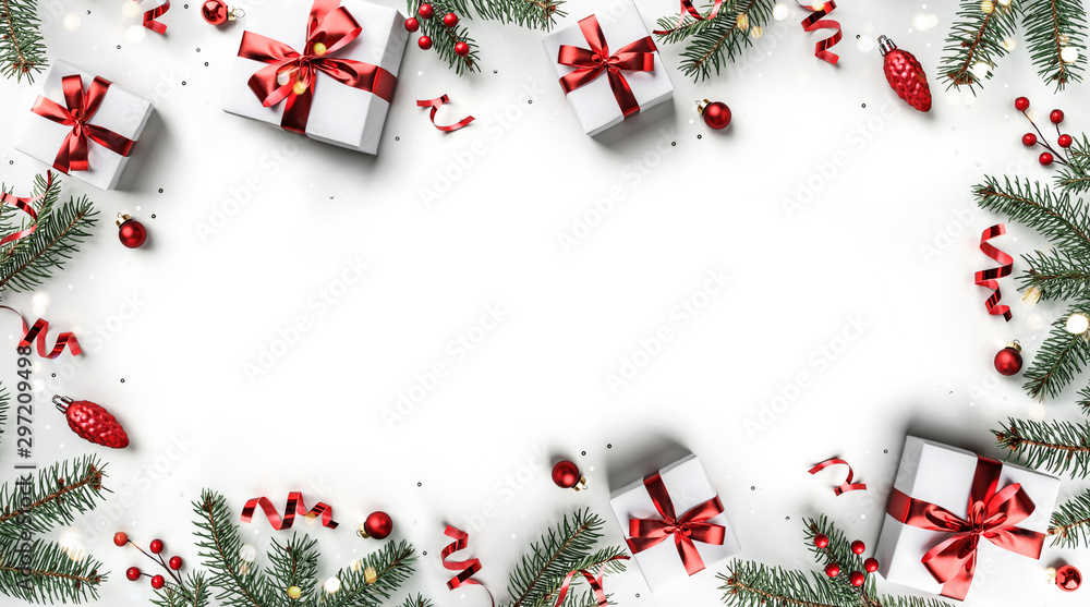 Creative frame made of Christmas fir branches, gift boxes, red decoration, sparkles and confetti on white background. Xmas and New Year holiday, bokeh, light. Flat lay, top view - obrazy, fototapety, plakaty 