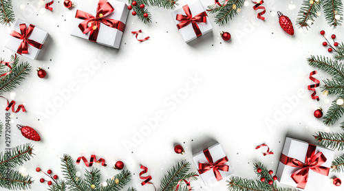 Creative frame made of Christmas fir branches, gift boxes, red decoration, sparkles and confetti on white background. Xmas and New Year holiday, bokeh, light. Flat lay, top view