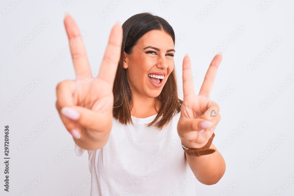 Portrait of beautiful and young brunette woman standing over isolated white background smiling looking to the camera showing fingers doing victory sign. Number two. Portrait of beautiful and young brunette woman standing over isolated white background smiling looking to the camera showing fingers doing victory sign. Number two.