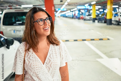 Young woman smiling confident at underground parking lot around cars and lights