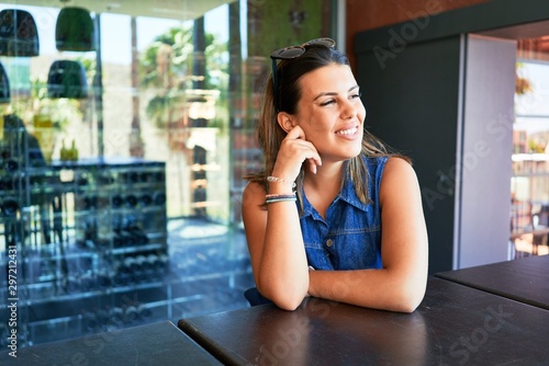 Young beautiful woman sitting at restaurant enjoying summer vacation